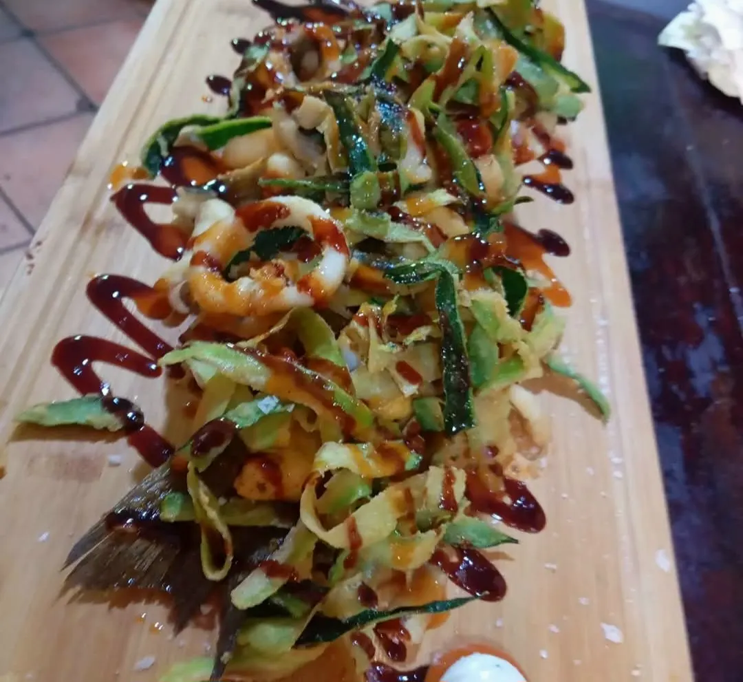 Tabla de madera con tiras de calabacín fritas y salsa por encima, de El Togo