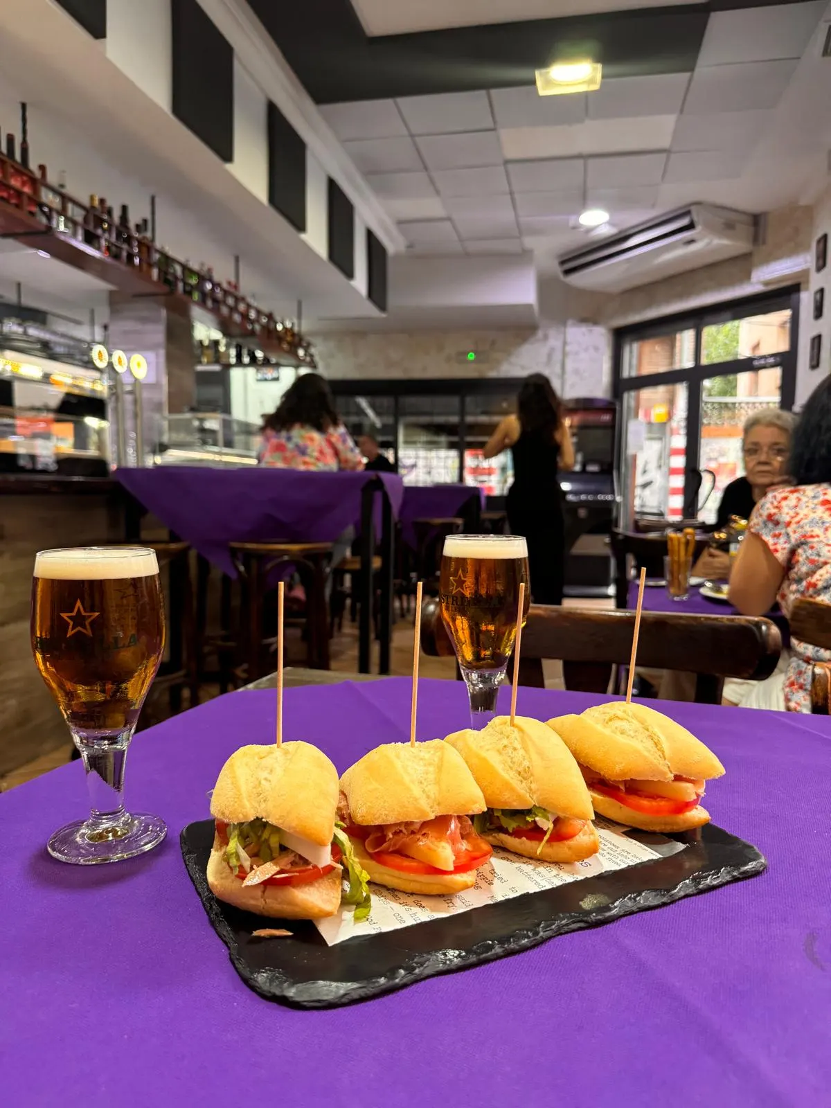 Cuatro montaditos servidos en una pizarra sobre una mesa de El Togo