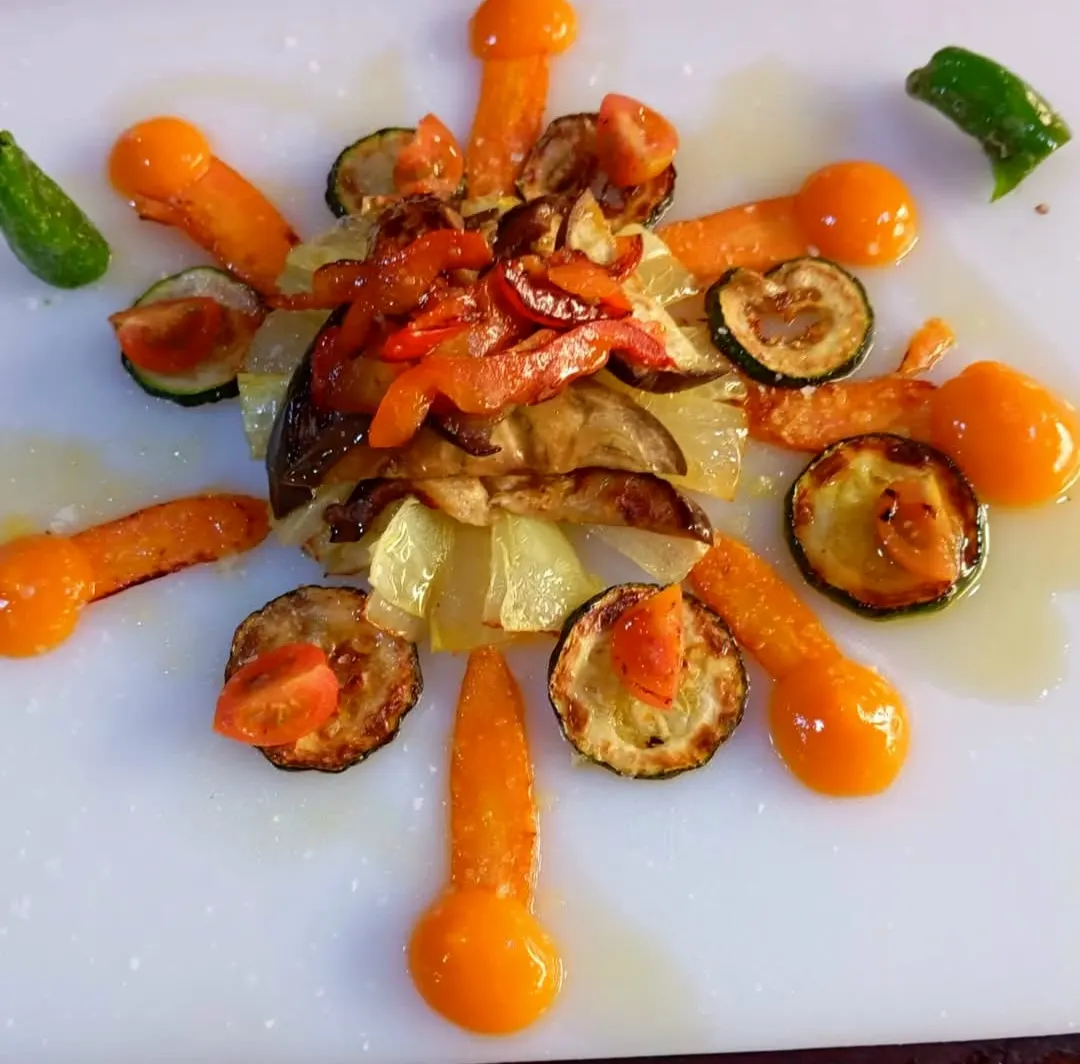 Verduras a la plancha con calabacín, pimiento y puntos de salsa naranja en un plato blanco de El Togo