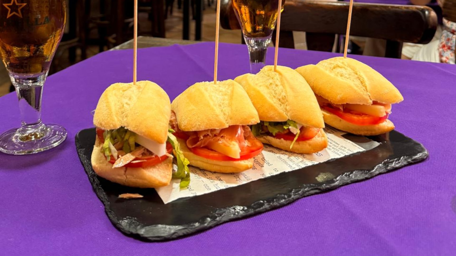 Cuatro montaditos sobre una pizarra y un mantel morado